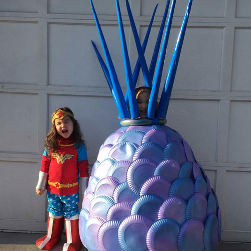 two girls in costumes, one is wonder woman and the other is wearing an elaborate handmade costume of a prehistoric invertebrate creature